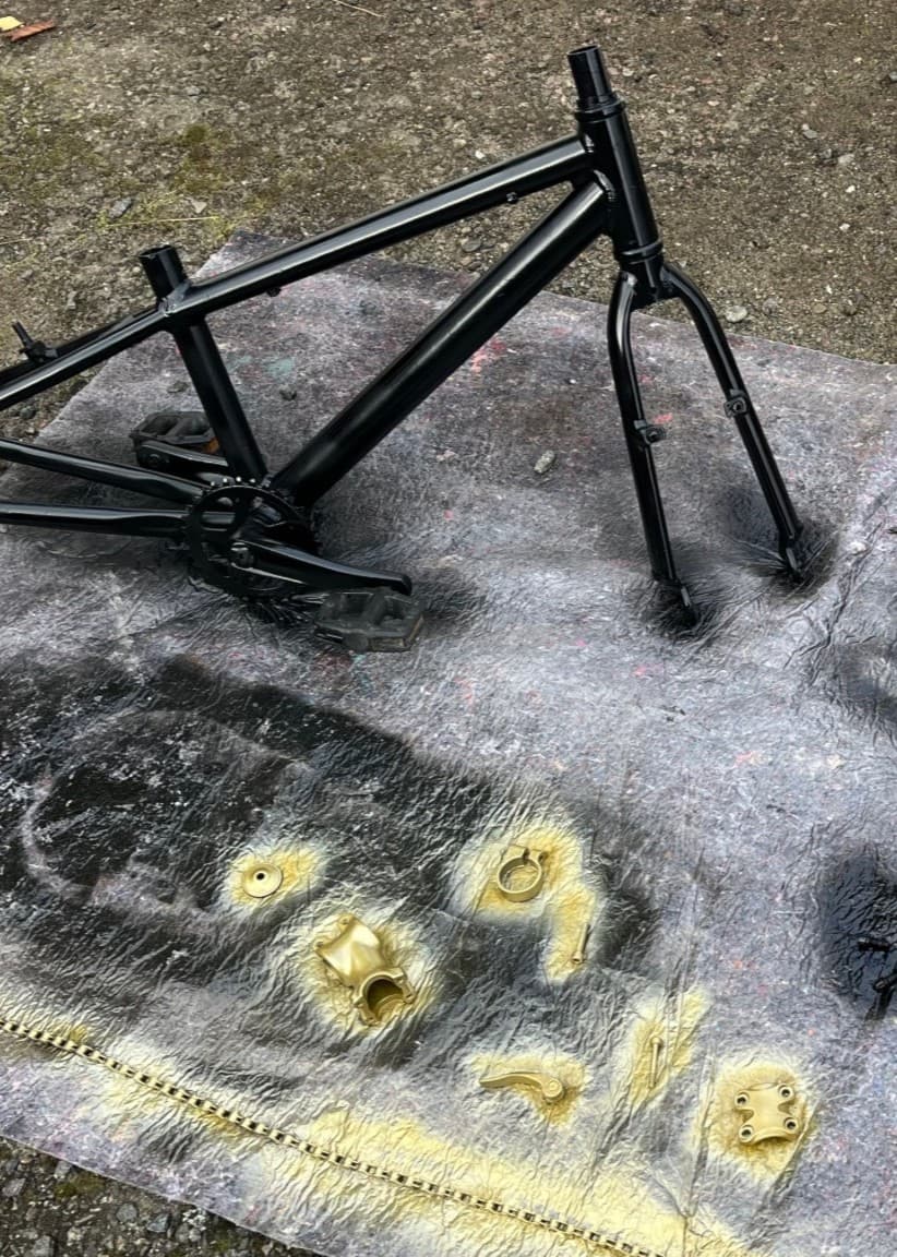 Splittbild. I vänstra delen av bilden syns föredetta proffsboxaren Armand Krajnc som står framför en mörkblå bakgrund. Han bär en ljus skjorta och har en neutral uppsyn. I högra bilden syns en cykelram, cykelsadel och andra cykeldelar ligger på asfalten omgiven av svart och guldig sprayfärg.