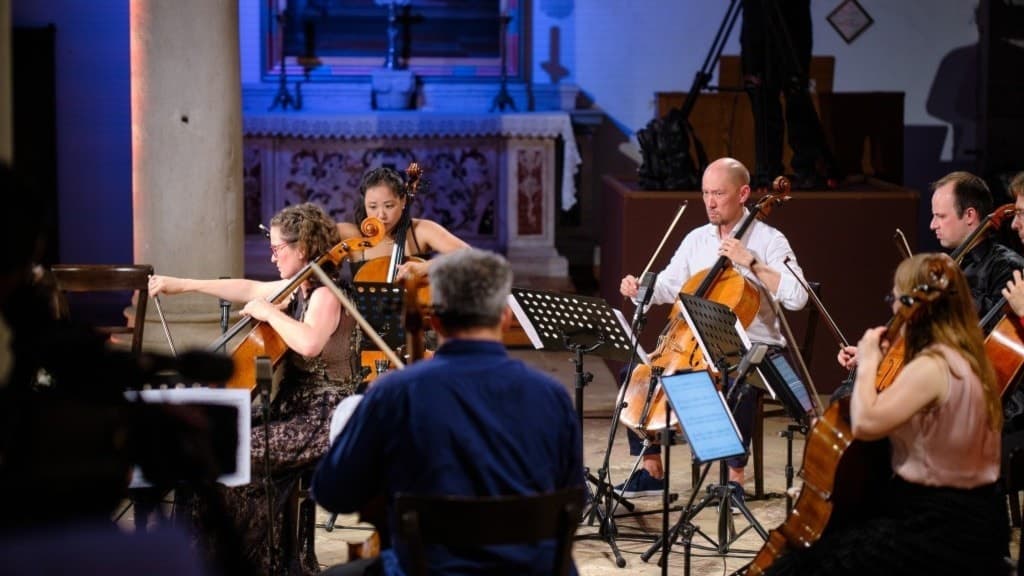 Åtta cellister spelar en konsert i en kyrka. 