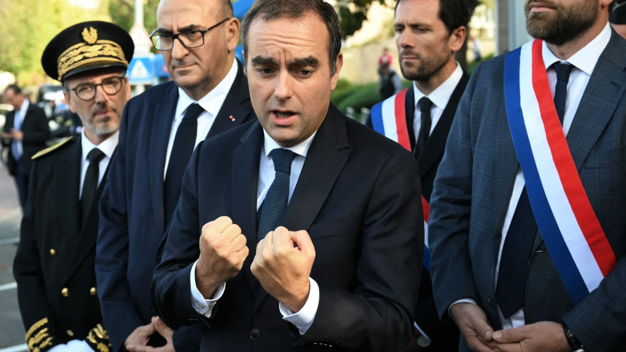 Frankrikes premiärminister Sébastien Lecornu talar med journalister utanför en polisstation i L'Hay-les-Roses, Paris, omgiven av politiker och tjänstemän, inklusive Vincent Jeanbrun och Mathieu Lefevre.