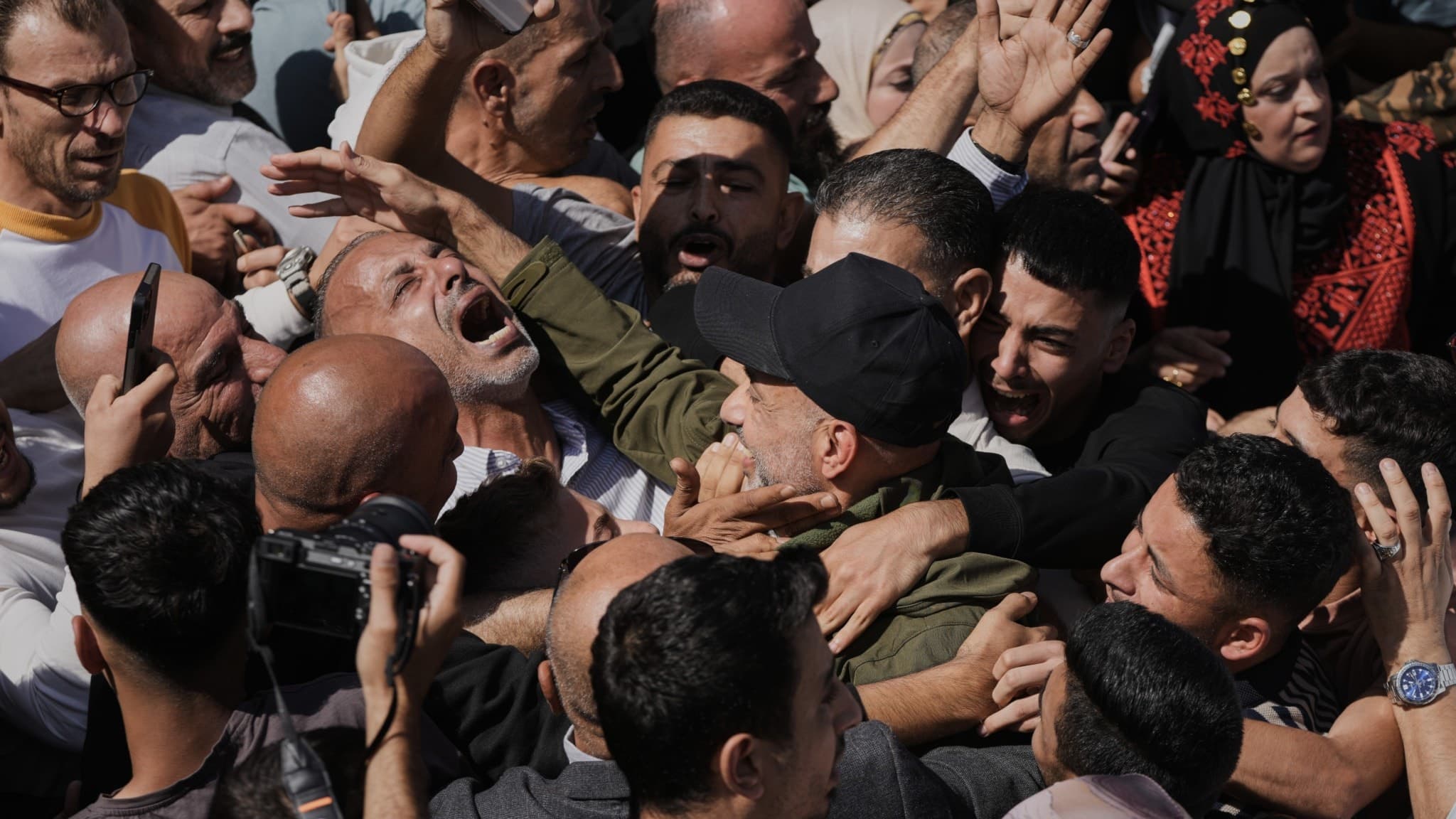 Flera palestinska män omfamnar och firar nyligen frigivna fångar i Ramallah, Västbanken.