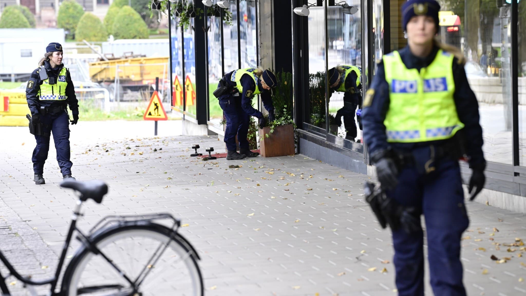 En gata med butiker, restauranger och en cykel i förgrunden. Och tre poliser.