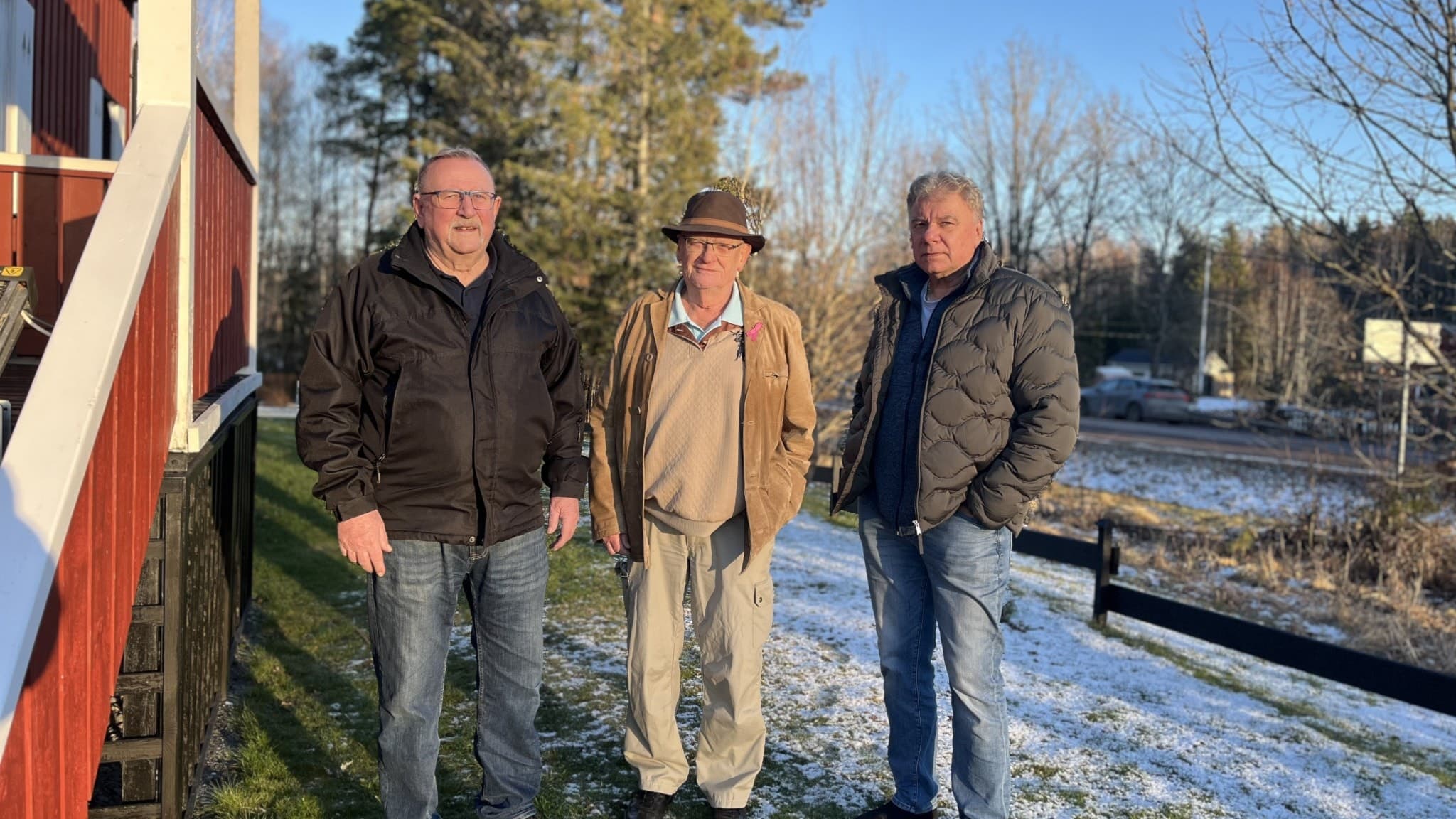 Tore Olsson, Börje Nyström och Staffan Marelius står utanför ett rött hus. De tittar allvarligt in i kameran. 