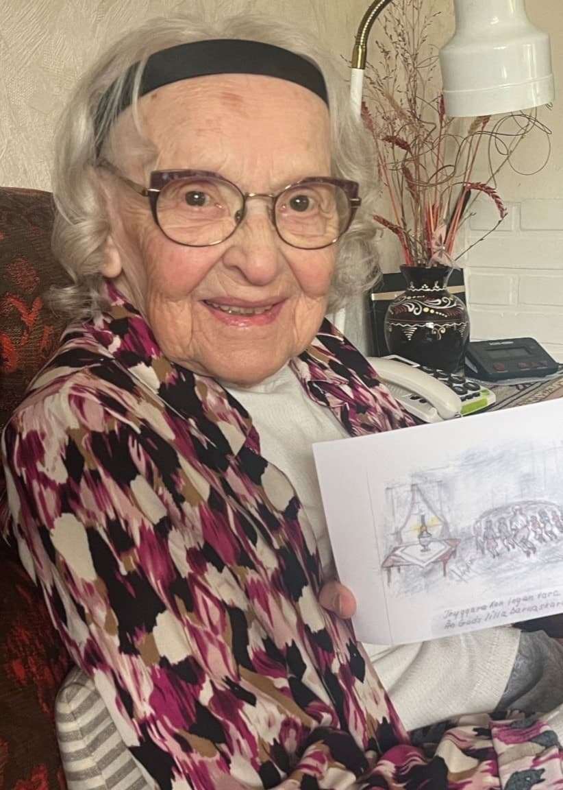 Vera Flink i sitt soffhörn, med en teckning hon gjort efter minnen från barndomen. 
