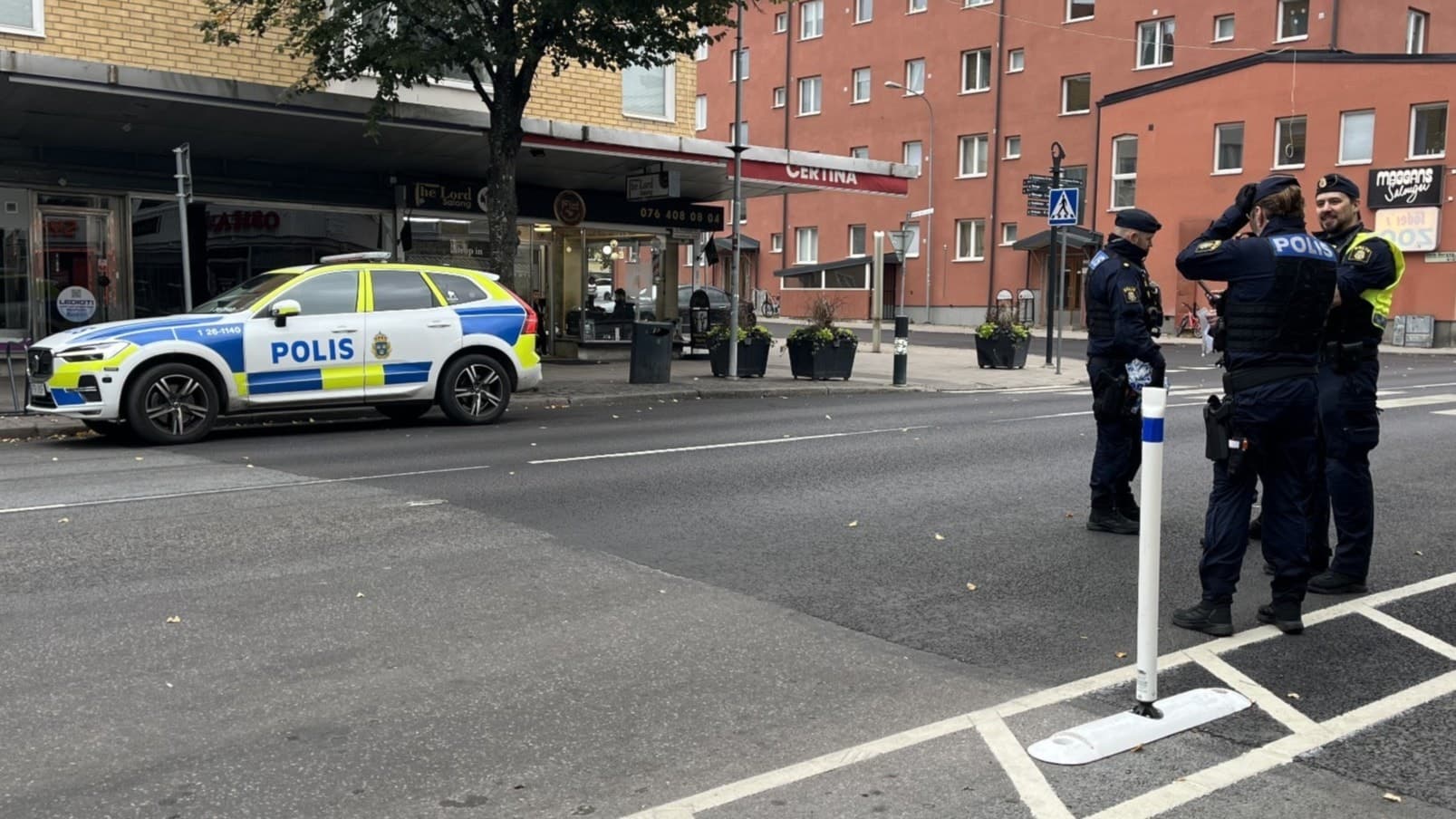 En gata med butiker, restauranger och en cykel i förgrunden. Och tre poliser.