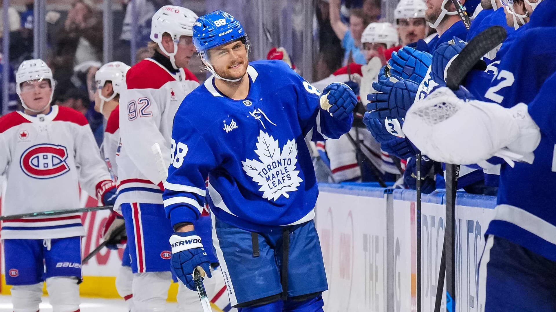 William Nylander iklädd blå Toronto-tröja gör fistbumps med sina lagkamrater efter mål. Foto: TT