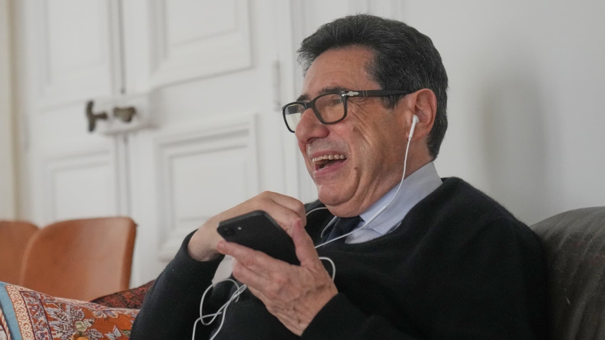 Philippe Aghion, vinnare av Nobelpriset i ekonomi, sitter avslappnat i en soffa med hörlurar och mobiltelefon.