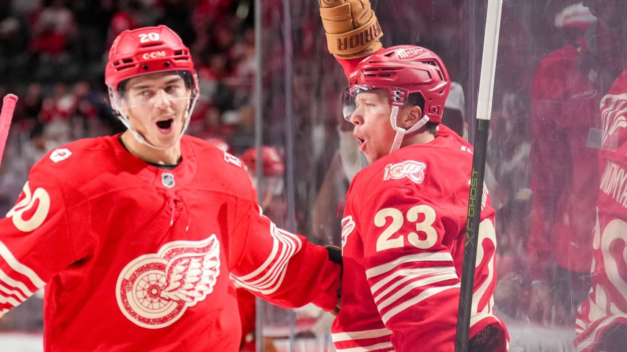Albert Johansson och Lucas Raymond i Detroit Red Wings firar ett mål mot Toronto Maple Leafs under en NHL-match på Little Caesars Arena. Båda spelarna bär röda matchtröjor med lagets logotyp.