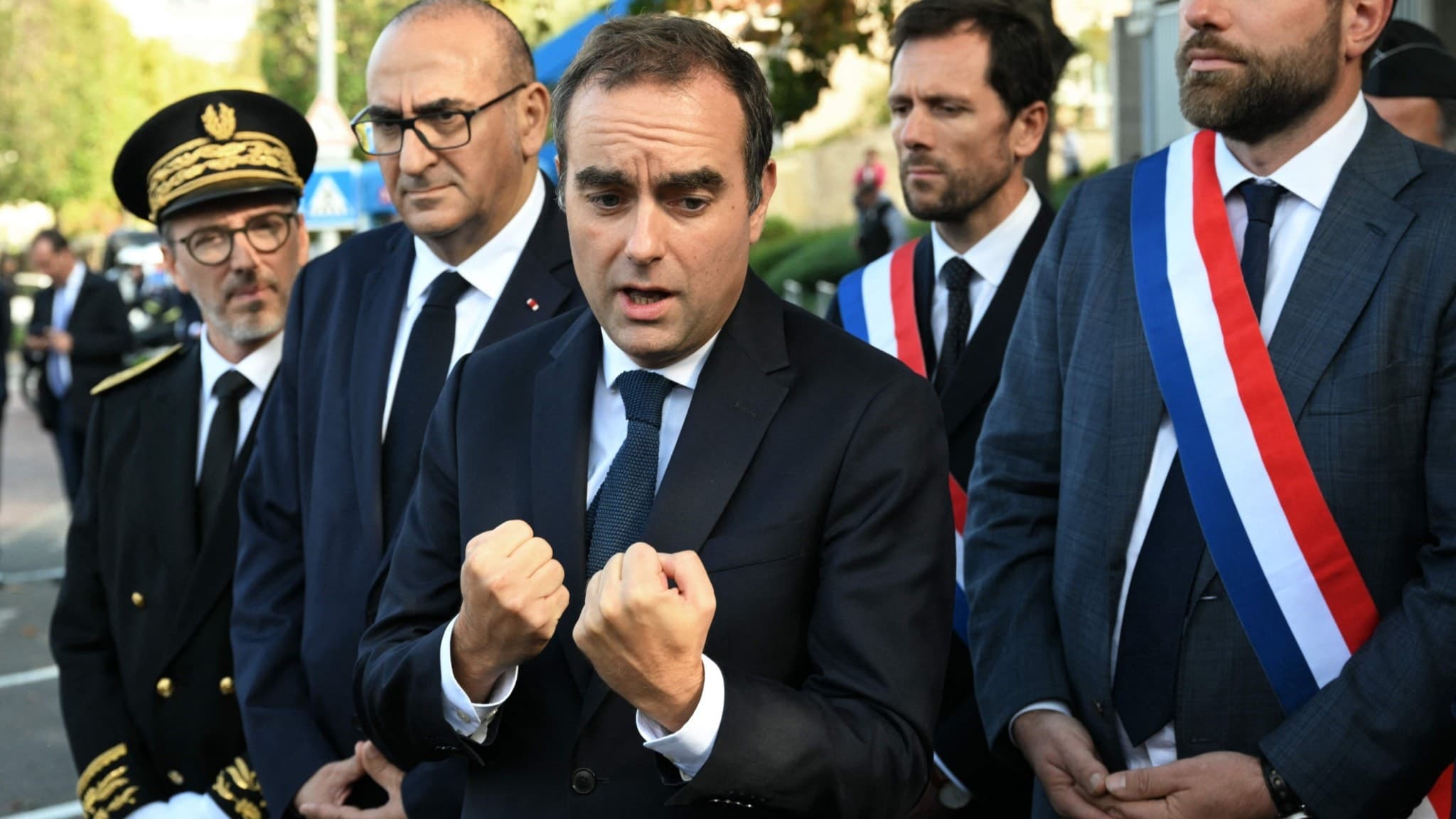 Frankrikes premiärminister Sébastien Lecornu talar med journalister utanför en polisstation i L'Hay-les-Roses, Paris, omgiven av politiker och tjänstemän, inklusive Vincent Jeanbrun och Mathieu Lefevre.