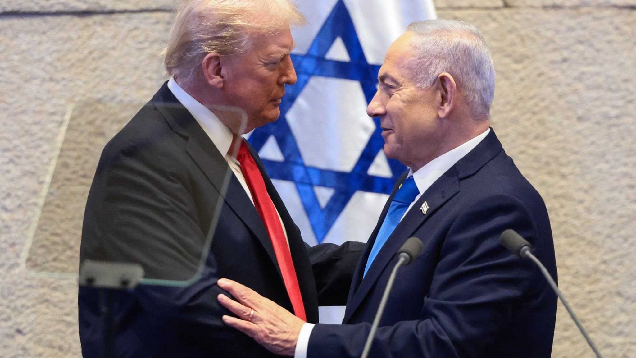 USA:s president Donald Trump och Israels premiärminister Benjamin Netanyahu samtalar framför en israelisk flagga i Knesset, Jerusalem.