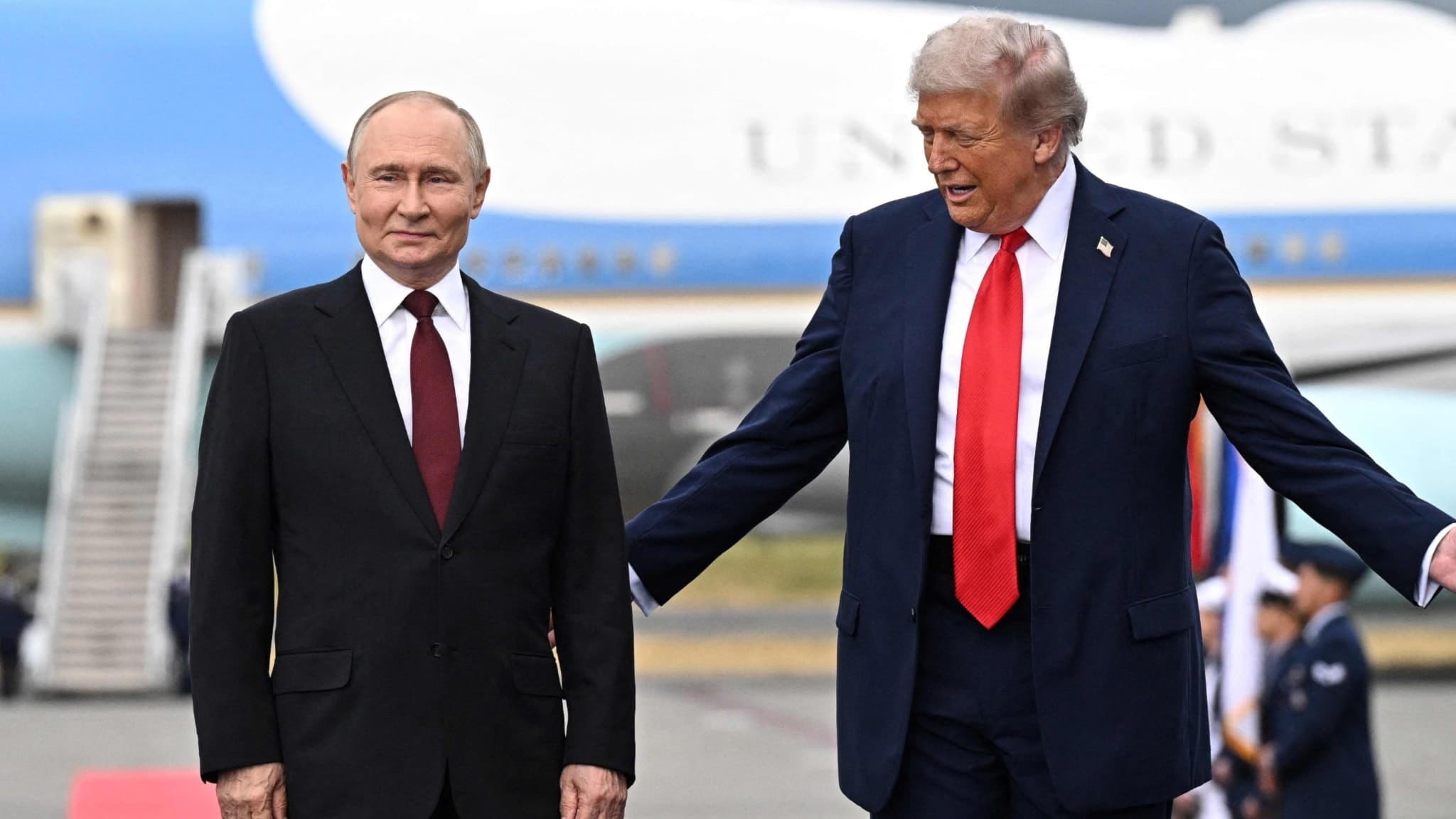 Donald Trump och Vladimir Putin står på en röd matta framför flygplanet Air Force One under ett toppmöte om Ukraina på en militärbas i Alaska. Trump gestikulerar med öppna armar.