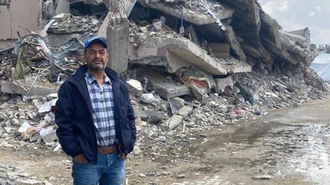 Samir Abu Salem framför ruiner på en gata i Gaza.